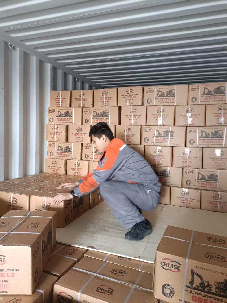 Cruise Grease worker packing 1 kg grease cartons into an export container